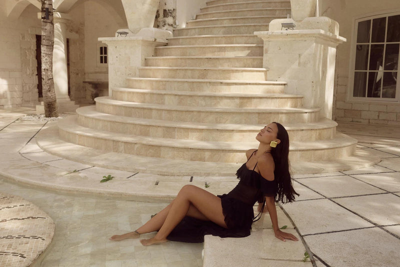 Woman in black dress sitting with feet in pool